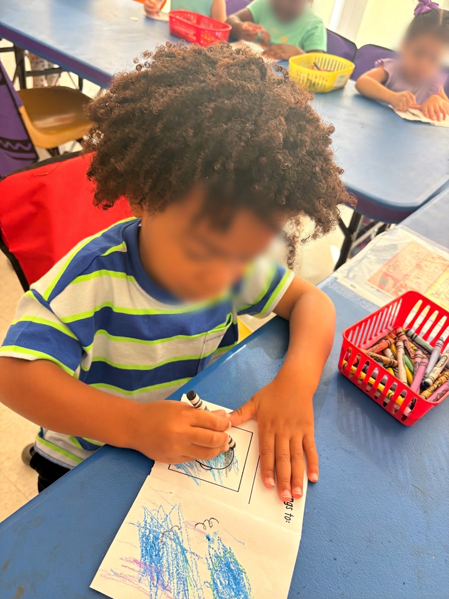 Focused little one crayoning a self-portrait